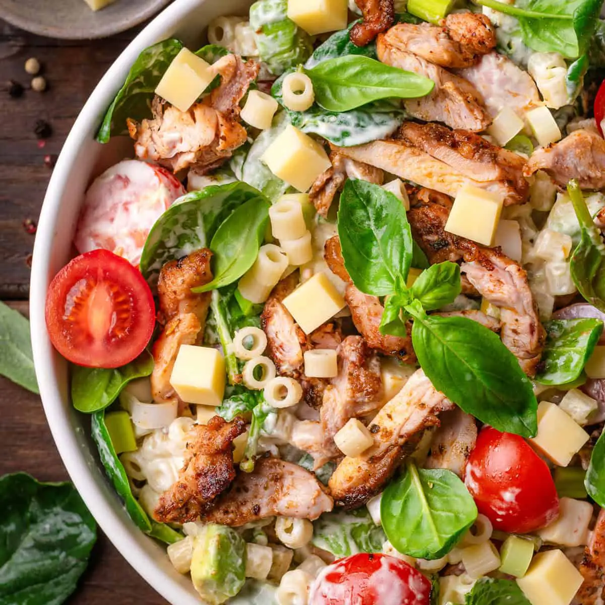 Creamy chicken pasta salad with mayonnaise and fresh herbs in a white bowl