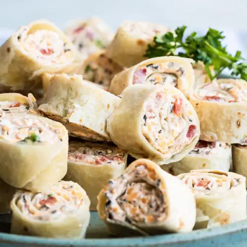 Taco tortilla roll-ups appetizer with creamy cheese and green chilies, sliced into bite-sized pieces on a serving plate
