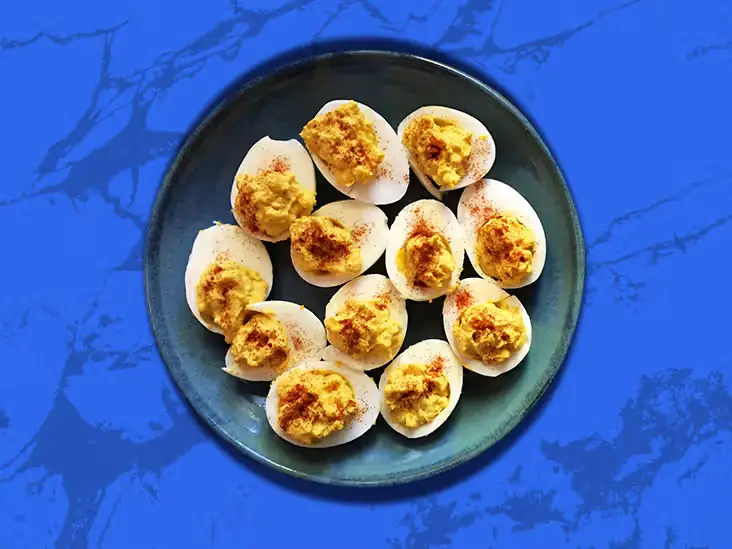 An assortment of deviled eggs from around the world, featuring diverse fillings, spices, and garnishes inspired by global cuisines, displayed on a serving platter.