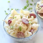 Colorful pasta salad served in a square dish with fresh vegetables