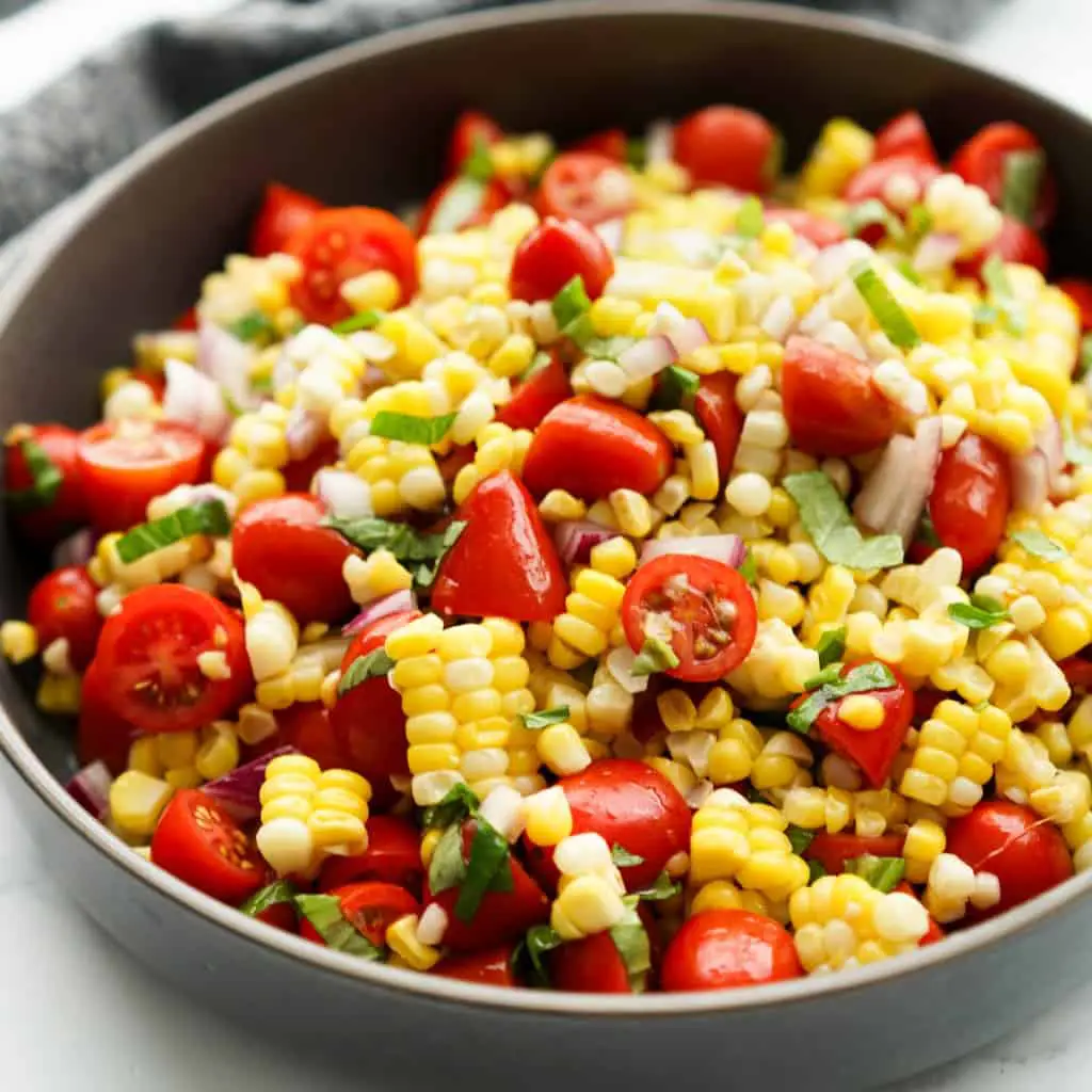 Colorful summer tomato and corn salad with basil and olive oil