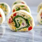 Veggie tortilla pinwheels with colorful vegetables and cream cheese filling, sliced into bite-sized rolls for a healthy appetizer