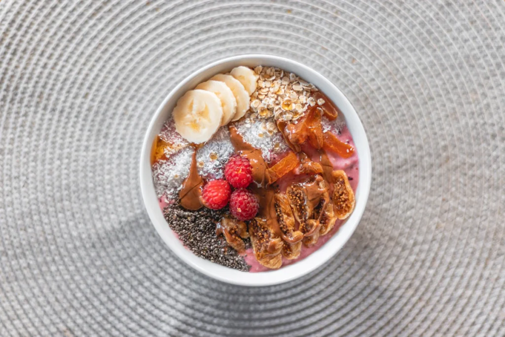 Bowl of oats topped with sliced banana and raspberries
