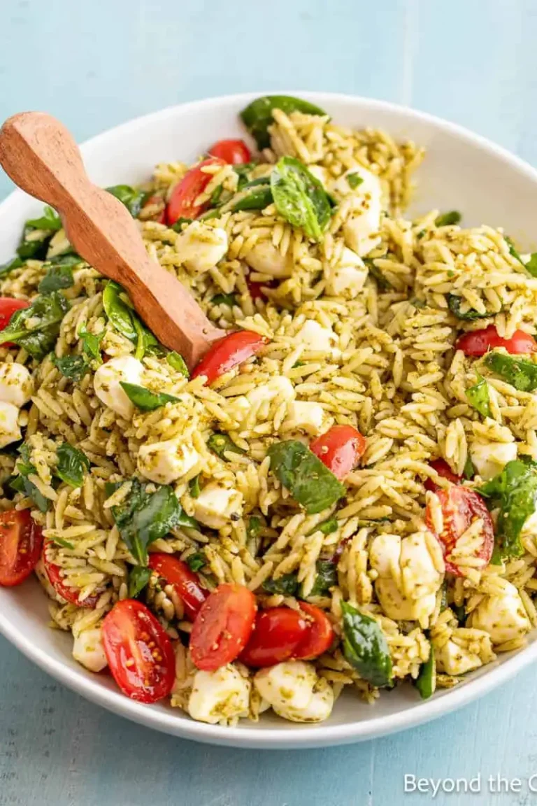 Chicken pesto orzo salad with cherry tomatoes and fresh basil in a white bowl