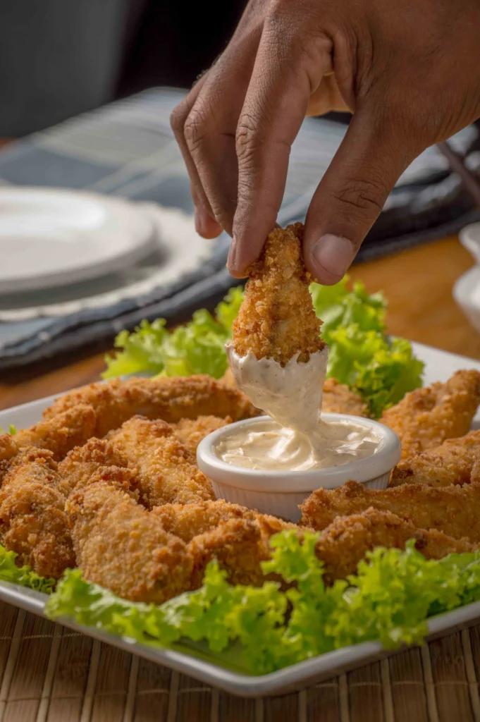 Dipping a chicken tender into creamy sauce