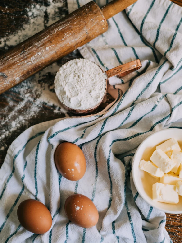 Bread baking ingredients: flour, eggs, and dairy in bowls on a linen cloth