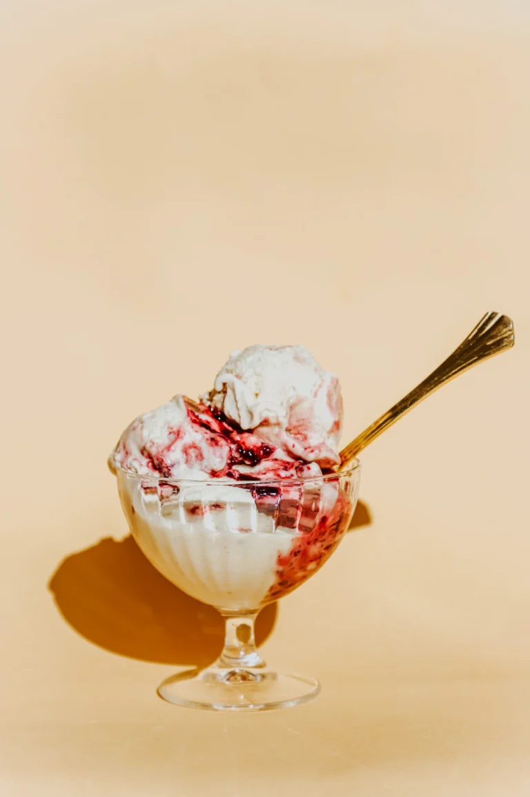 Two scoops of creamy cottage cheese ice cream with a berry swirl in a glass bowl