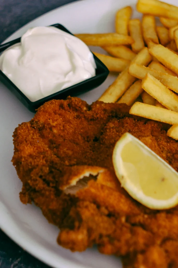 Crispy chicken cutlet with lemon wedge and fries