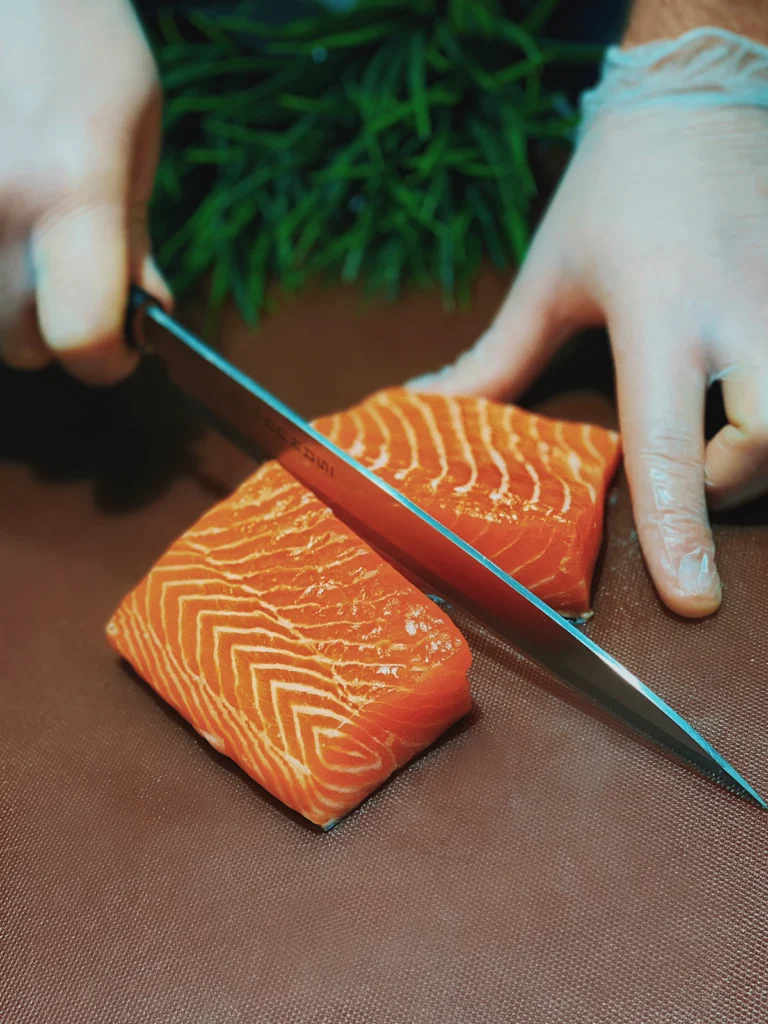 Cutting a fresh salmon fillet into cubes with a knife