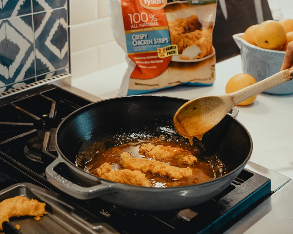 Chicken tenders frying in a skillet of hot oil