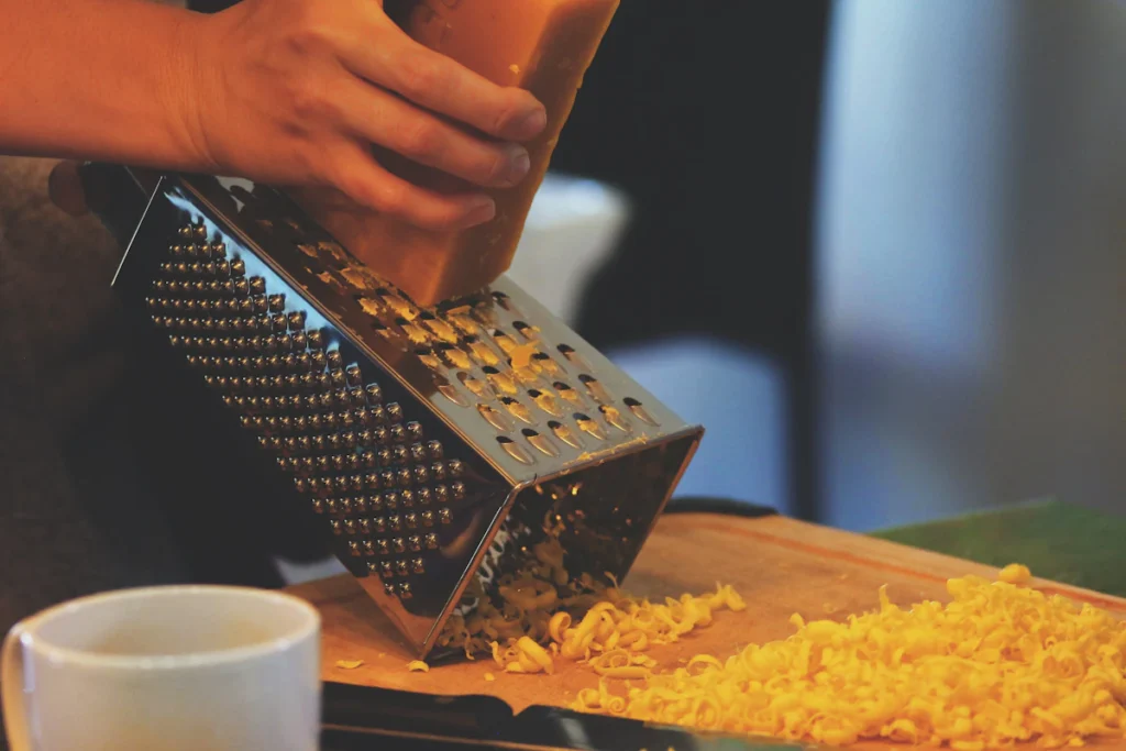 Grating sharp cheddar cheese on a box grater