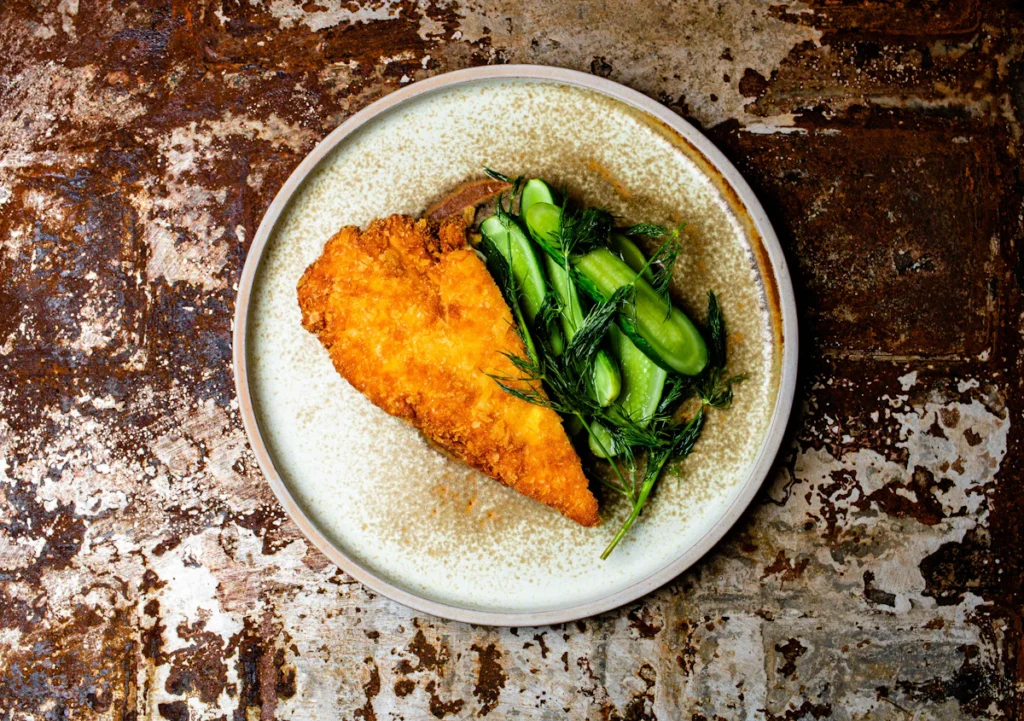 Lemon chicken cutlet served with greens