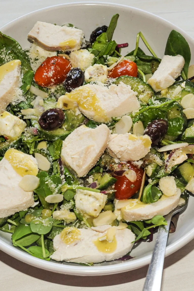 Lemon herb Mediterranean chicken salad with spinach, tomatoes, olives and feta in a bowl