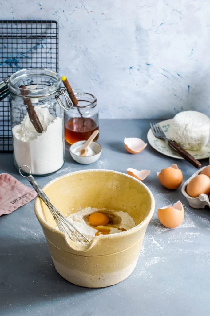 Muffin baking ingredients: flour, eggs, butter, and mixing bowl on a counter