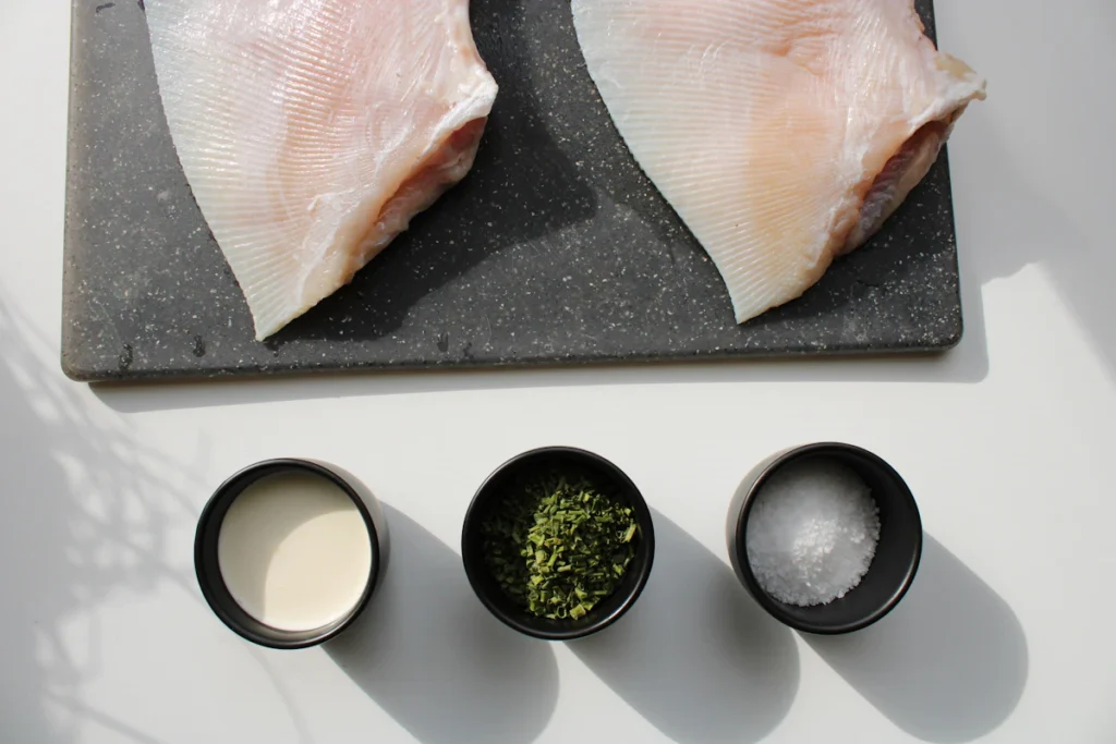 Raw boneless chicken breasts seasoned on a cutting board
