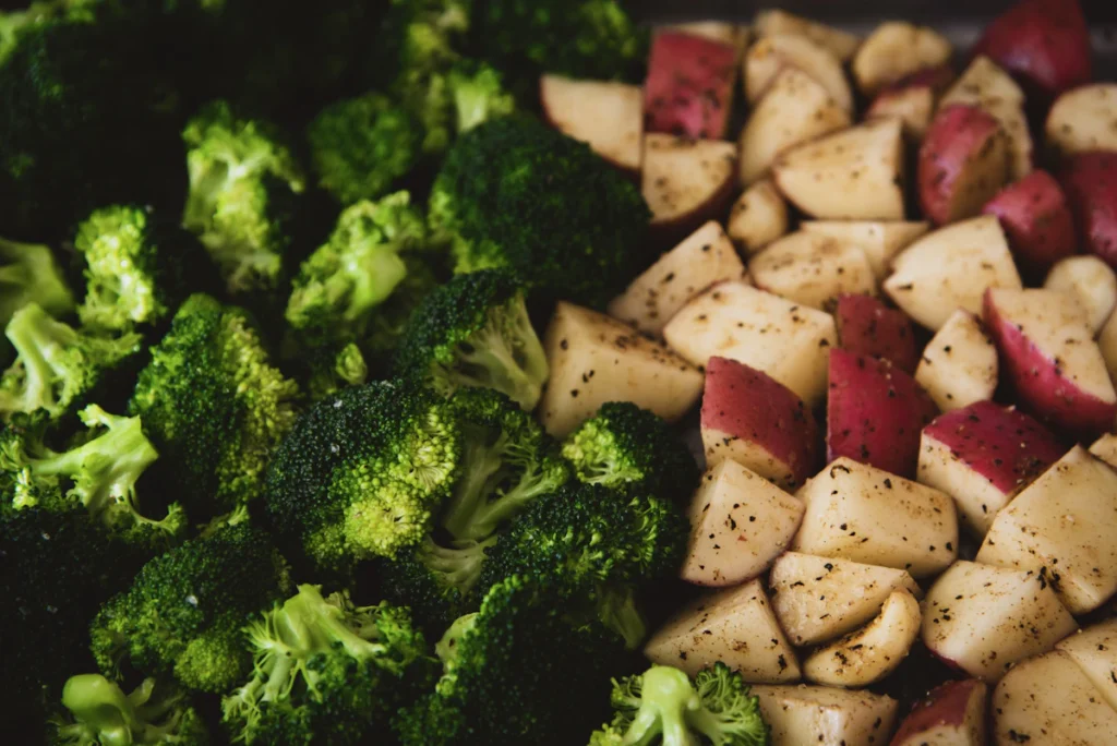 Roasted broccoli florets and potato cubes on a baking sheet