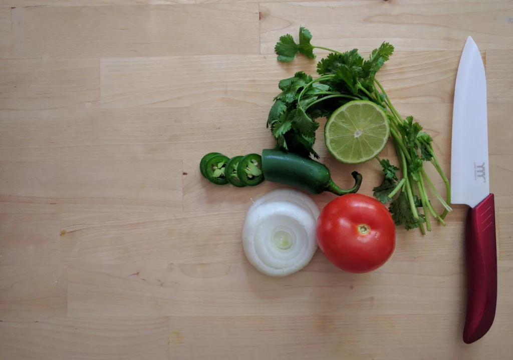 Salsa fresca ingredients: tomato, jalapeño, onion, cilantro, and lime on a cutting board