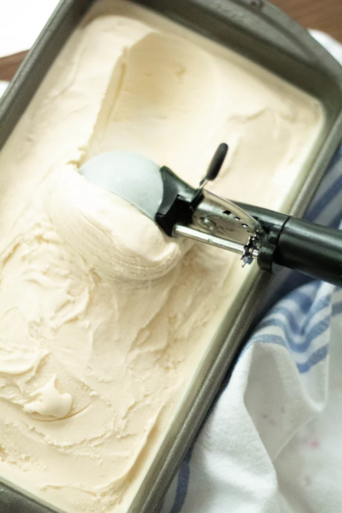 Scooping creamy ice cream from a freezer container