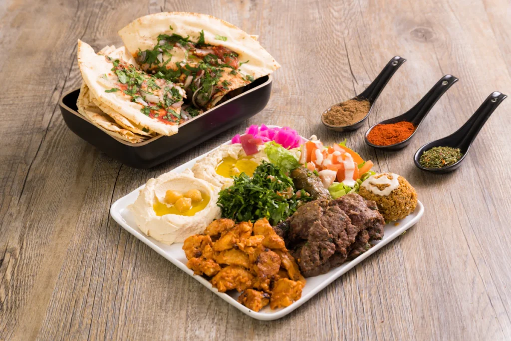 Spoons of cumin, paprika and turmeric beside a shawarma plate