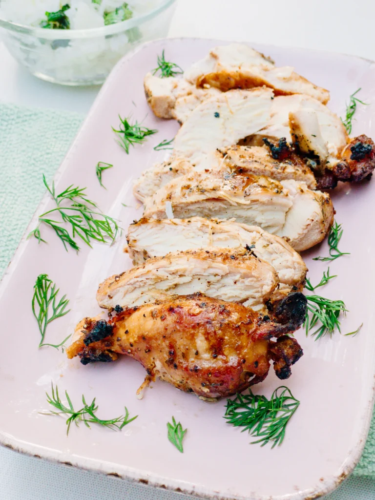 Sliced golden roasted chicken breast with herbs on a plate