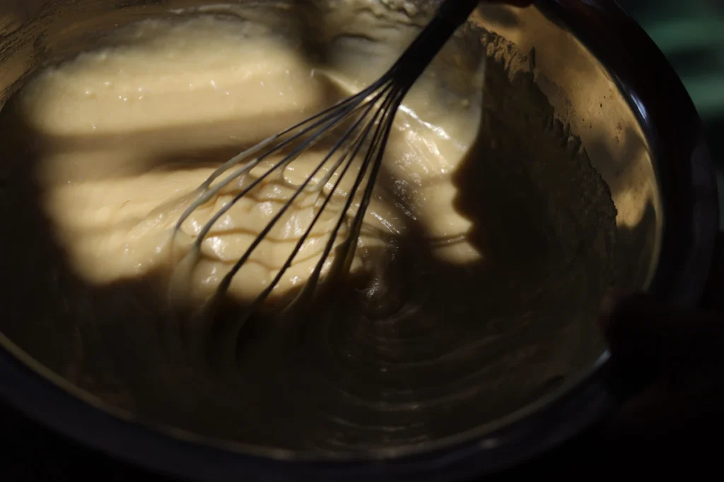 Whisk mixing a smooth creamy batter in a bowl