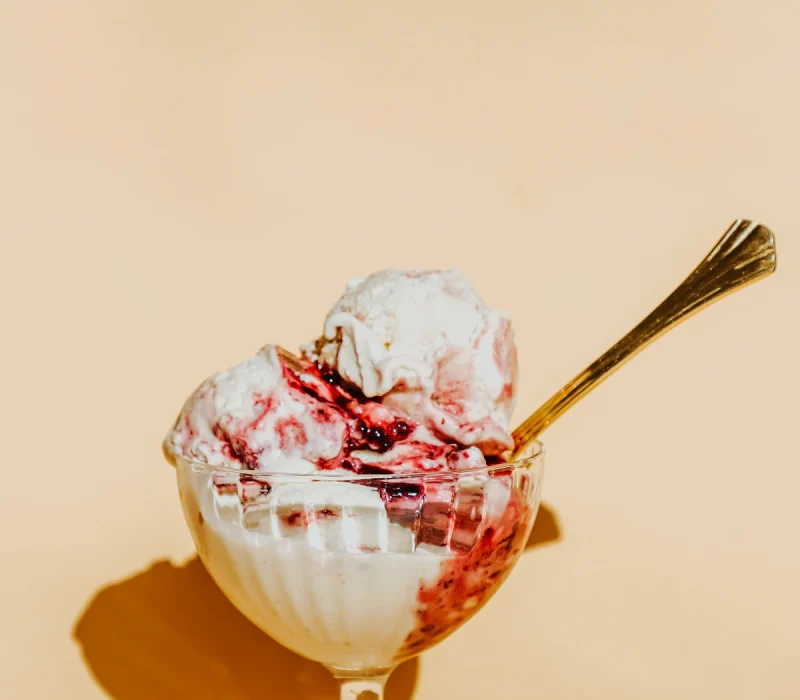 Two scoops of creamy cottage cheese ice cream with a berry swirl in a glass bowl