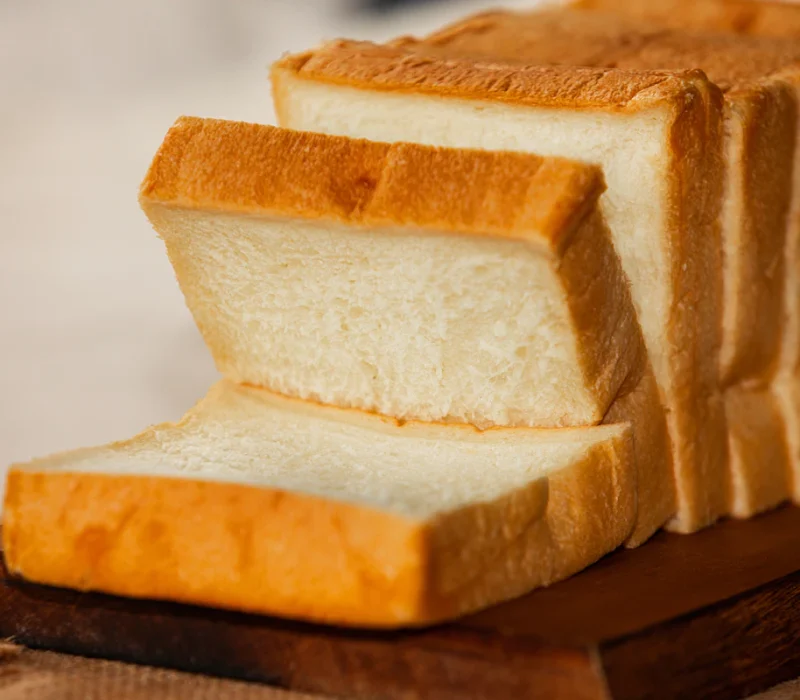 Sliced soft cottage cheese protein bread loaf on a wooden board