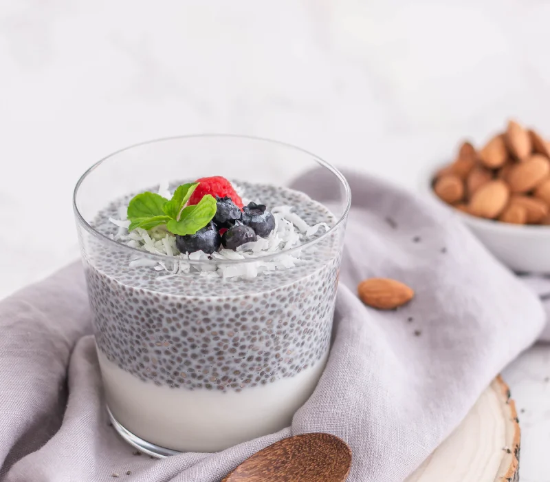 High protein chia pudding in a glass topped with berries and almonds